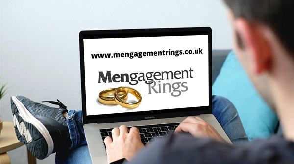 laptop screen displaying two gold mengagement rings with male browsing for rings